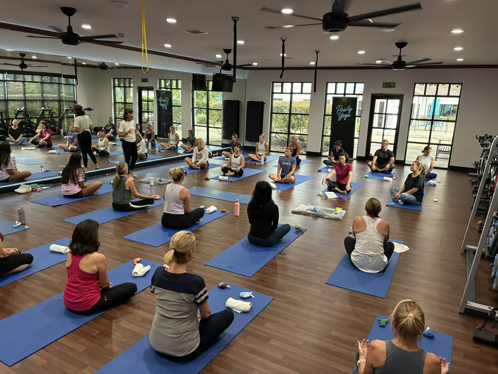 An adult team seated on mats at a Houston corporate puppy yoga event