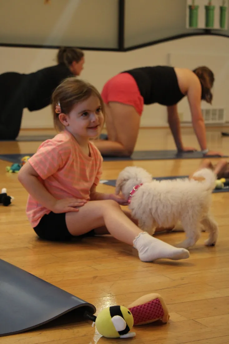 Smiling guest with a puppy during a Houston puppy yoga session