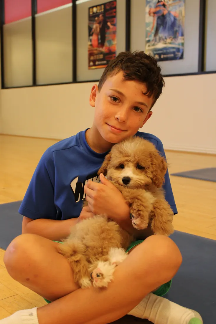 Young guest cradling an apricot puppy at Pawty Yoga Houston