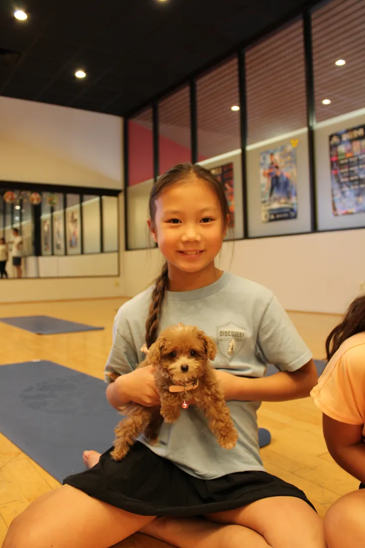 Kid holding a puppy at Pawty Yoga Houston's family-friendly session