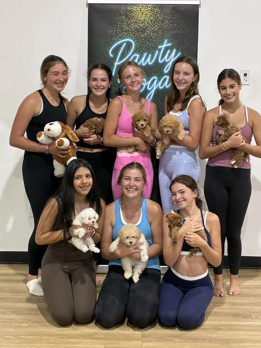 A group holding a full litter of puppies at a private Pawty Yoga birthday party in Houston