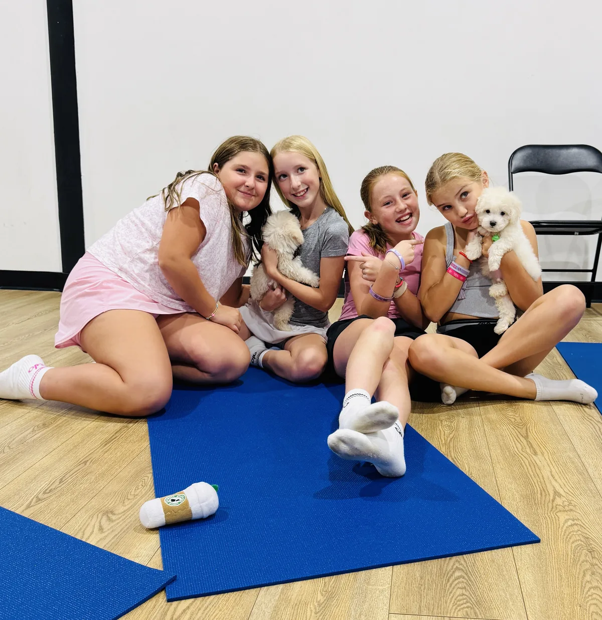 Four friends on mats with puppies at a tween birthday party in Houston