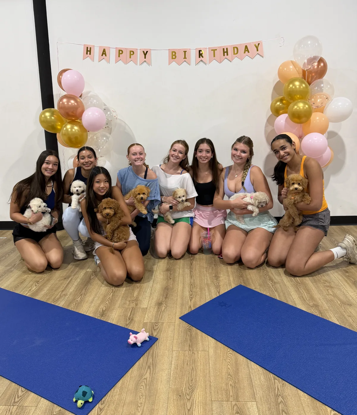 Birthday guests with puppies under a Happy Birthday banner at a private Houston party