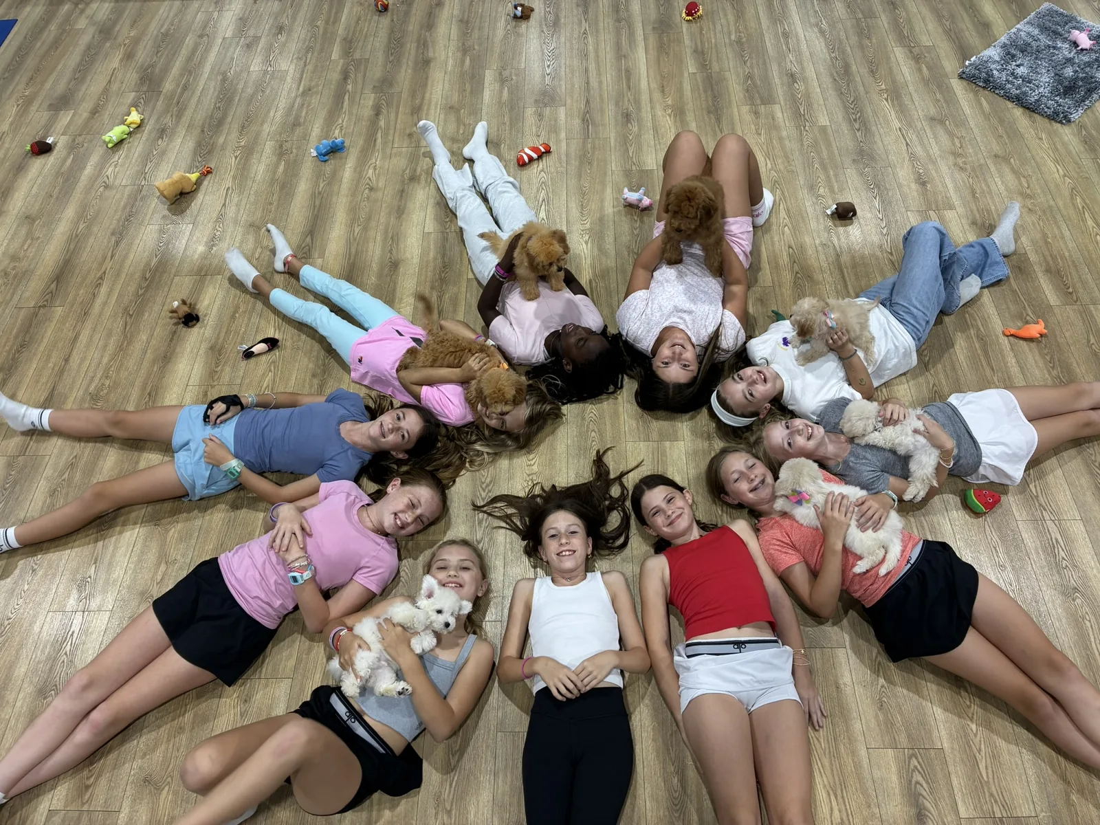 Kids lying in a star shape with puppies at a Pawty Yoga kids session in Houston