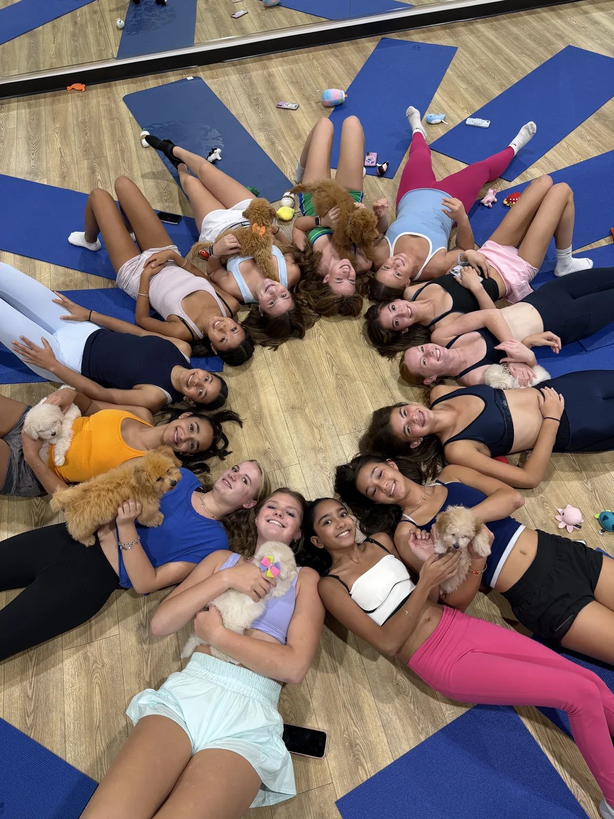 Teens lying in a circle with puppies at a Houston birthday party