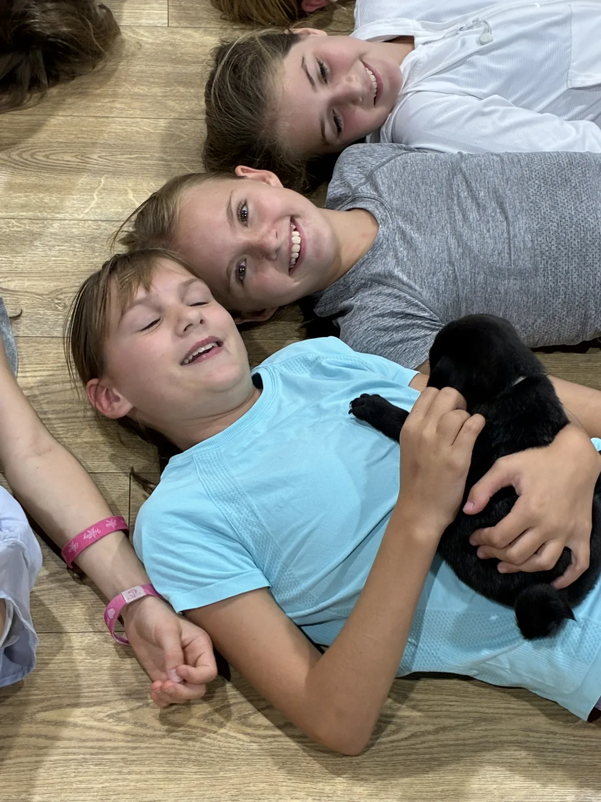 Two kids cuddling a black puppy on the floor at a Houston kids session